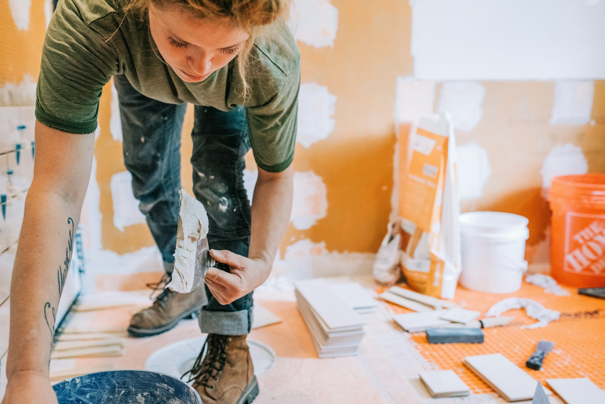 A Woman Worker Scooping Mud (Mortar) in a bathroom remodel